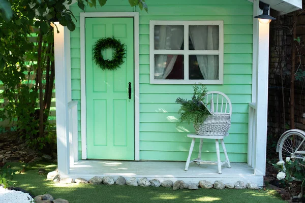 Decor home outdoor of summer yard. Exterior Wooden porch home with garden furniture. Facade green wooden house decorated for spring holidays. Interior cozy veranda house  with chair and basket flowers
