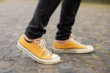 Close up Feet of man while walking commuting to work. Male in yellow sneakers being walking down the street. Confident man Feet Walking In City. Man Legs In in shoes Walking on sidewalk. 