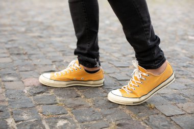 Close up Feet of man while walking commuting to work. Male in yellow sneakers being walking down the street. Confident man Feet Walking In City. Man Legs In in shoes Walking on sidewalk. 
