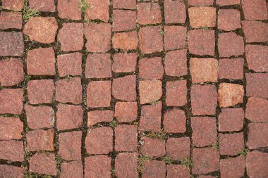 Red old brick paving stones background. Road surface made of brown rectangular stones. Close up of the detail of colorful cobblestones in an old street. An old road paved with granite stones. 