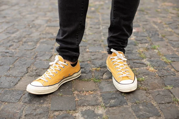 Close up Feet of man while walking commuting to work. Male in yellow sneakers being walking down the street. Confident man Feet Walking In City. Man Legs In in shoes Walking on sidewalk.