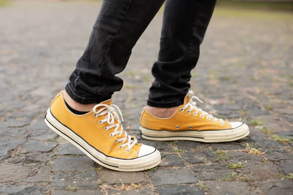 Close up Feet of man while walking commuting to work. Male in yellow sneakers being walking down the street. Confident man Feet Walking In City. Man Legs In in shoes Walking on sidewalk.