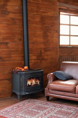 Classic black cast iron fire place with wood burning inside of it. Fragment of the interior of a country house. The iron furnace is heated. Wood burning stove, traditional heating system. 