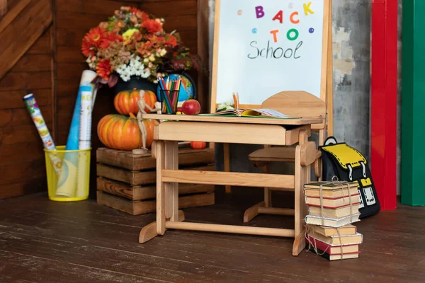 Empty classroom with blackboard and wooden table. Kindergarten. Interior of elementary school. Chalkboard, backpack, pencils and stationery on classroom. Teachers Day. Back to school.