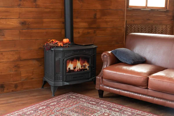 Classic black cast iron fire place with wood burning inside of it. Fragment of the interior of a country house. The iron furnace is heated. Wood burning stove, traditional heating system.