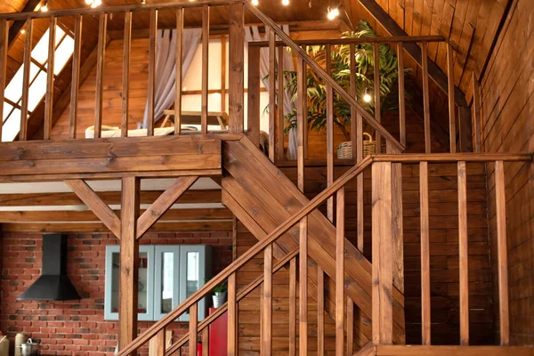 Modern staircase with wooden steps in flat. Wooden Stairway goes up. Country wooden house is spacious on two levels. Room with wooden stairway leading to second floor of modern flat.