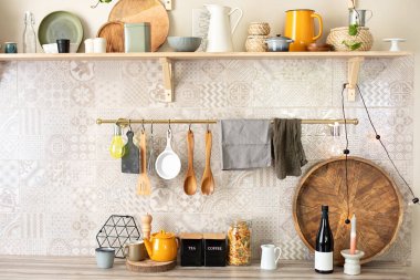 Mutfak gereçleri ve mutfak aletleri ahşap bir tezgahın üzerinde. Şık bir mutfak. Metal parmaklıklarda asılı ahşap mutfak aletleri. Seramik tabaklar, tabaklar ve sofrada rahat bir dekor