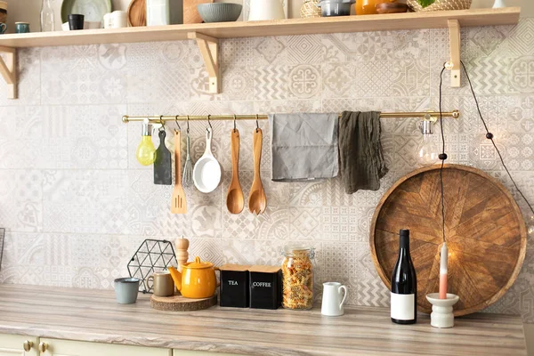 木制厨房用具挂在金属栏杆上 木制台面上的厨房用具和器皿 时尚的厨房内部 餐桌上的陶瓷盘 盘子和舒适的装饰 — 图库照片