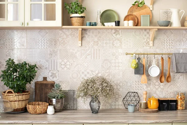 Stylish scandi cuisine interior decor. Ceramic plates, dishes, utensils and cozy decor on wooden shelfs. Kitchen wooden shelves with various ceramic jars and cookware. Open shelves in the kitchen.