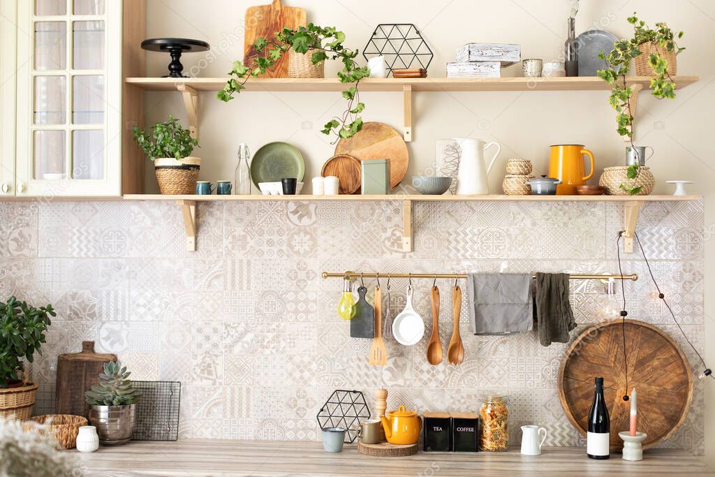 Ceramic plates, dishes, utensils and cozy decor on wooden shelfs. Kitchen wooden shelves with various ceramic jars and cookware. Open shelves in the kitchen. Stylish scandi cuisine interior decor. 