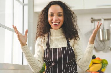 Güzel siyah kadın, beyaz mutfağın penceresinin yanında sürpriz yapıyor. Eş ya da ev hanımı aile için sağlıklı yemek pişirmeye hazırlanıyor. Evde kal..