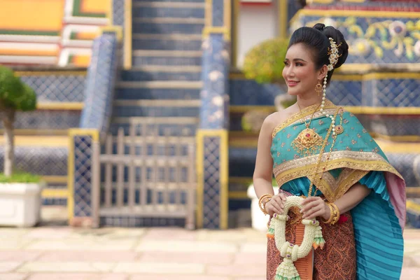 肖像画タイ民族衣装を着て笑顔アジアの女性は タイの人々のための重要な宗教的な日に花の庭で仏を崇拝する寺院の中にあります — ストック写真