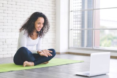 Güzel, genç, Latin, zayıf kadın canlı yayında eğitim alıyor ya da yatak odasında dizüstü bilgisayarla yoga öğreniyor. Evde kal ve Coronavirus covid-19 'un yayılması için kendini karantinaya al.