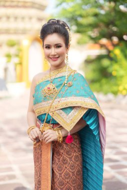 Asya 'lı kadınların gülümsemeleri ve Tayland ulusal kostümleri giymeleri Tayland halkı için önemli dini günlerde Buda' ya çiçek çelenkleriyle tapınmak içindir..