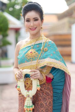 Asya 'lı kadınların gülümsemeleri ve Tayland ulusal kostümleri giymeleri Tayland halkı için önemli dini günlerde Buda' ya çiçek çelenkleriyle tapınmak içindir..