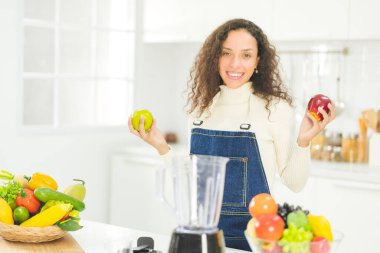 Portrait of beautiful woman is holding red and green apple in the bright white kitchen. wife or housewife is preparing to cook healthy food for the family. recive order for food delivery.