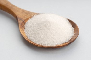 Gri arka planda Tahta Kaşıklı Şeker. Kapat.