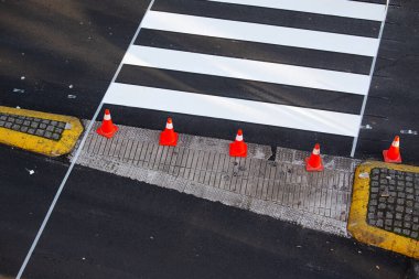 Şehir yolunda yeni boyanmış zebra koni ve asfaltta maske bandıyla karşıdan karşıya geçiyor.