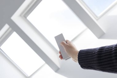 Woman Hand opening roof windows of a house with remote controller. Home automation clipart