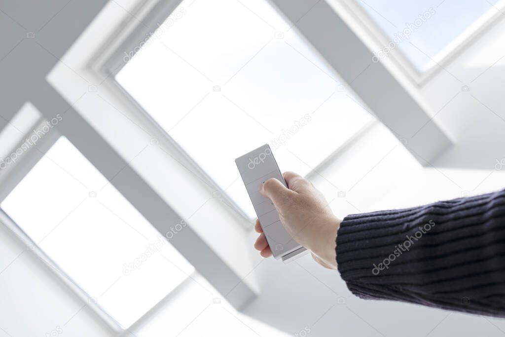 Woman Hand opening roof windows of a house with remote controller. Home automation