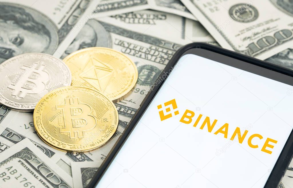 Galicia, Spain; january 28, 2022: Smartphone screen showing Binance logo and dollar banknotes and bitcoin and ethereum coins