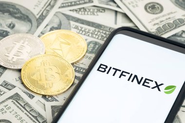 Galiçya, İspanya; 28 Ocak 2022: Smartphone ekranında Bitfinex logosu ve dolar banknotları ve bitcoin ve ethereum paralar