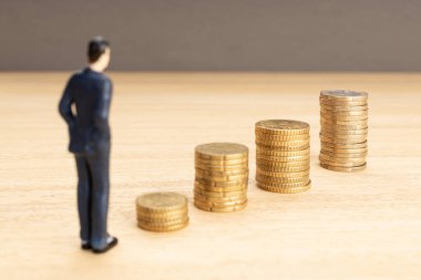 İstiflenmiş paraların büyümesine bakan bir iş adamı figürü. Muhasebe konsepti için para biriktiriyorum. Boşluğu kopyala