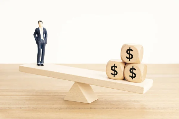Life and Work or money balance concept. Businessman figurine and dollar symbol on wooden blocks on wooden seesaw