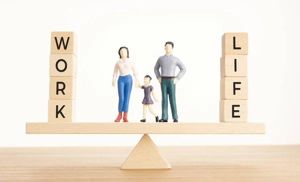 Balance Between Life And Work concept. Family figurines and Wooden blocks with word on Seesaw