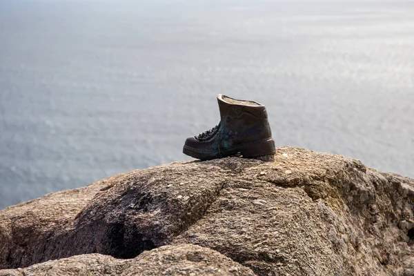 Cast bronze boot on the rocks at the end of Camino de Santiago. Finisterre, Spain.Copy space