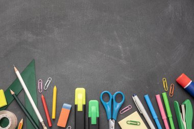 Back to school background with copy space. Variety of Office and school supplies on Blackboard background