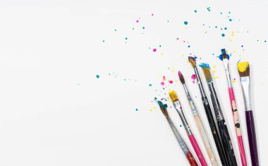Art Paint brushes with colorful splatter on white canvas paper. Copy space