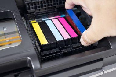 Human hand changing a blue ink cartridge of a multicolor inkjet printer