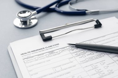 Health Insurance claim form and stethoscope on desk