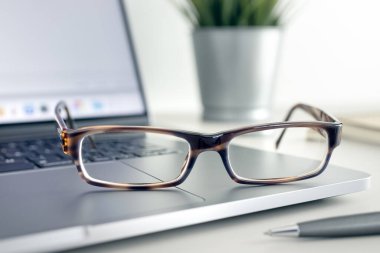 Close up of Eyeglasses on modern laptop on desk. Eye health and vision using computer and modern screen devices