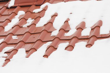 kırmızı bir çatı üzerinde eriyen kar