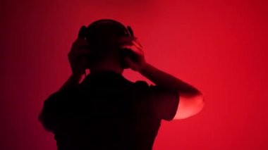 Excited young man in headphones is dancing in the club. Caucasian handsome talented man listening to music performing dance moves in neon room
