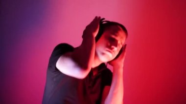 Attractive dancing man. Portrait in neon light. Music lover. Stereo technology. Dancing DJ tough guy with headphones lights up in a disco while performing in a nightclub