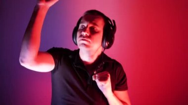 Attractive dancing man. Portrait in neon light. Music lover. Stereo technology. Dancing DJ tough guy with headphones lights up in a disco while performing in a nightclub