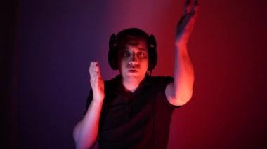 Modern rave. Dancing deejay cool guy wearing headphones lights up at the disco during performance in nightclub