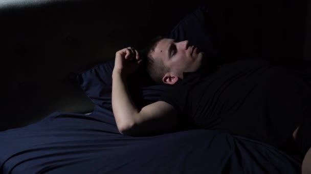 Störd sömn. Jag har mardrömmar. Den unga killen kastar och vänder sig i sängen. — Stockvideo