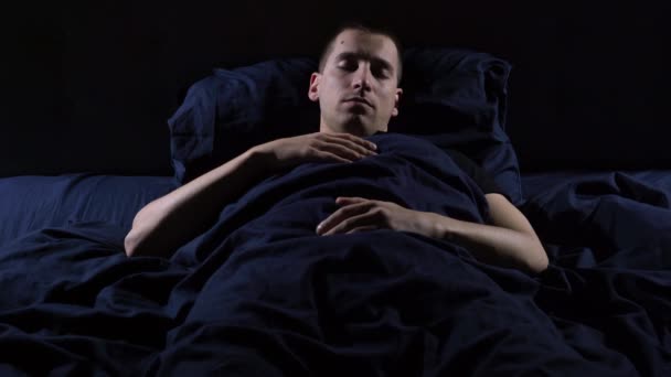 Forstyrret søvn. Jeg har mareridt. Den unge fyr kaster og drejer i sengen. – Stock-video