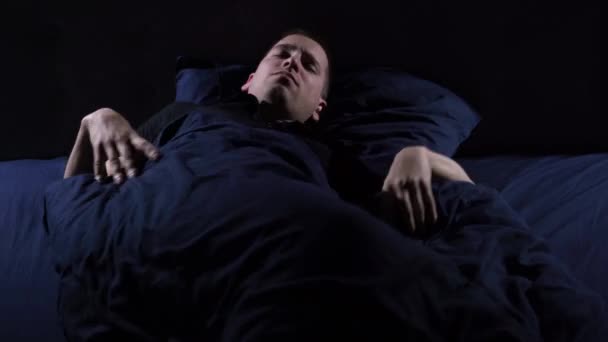 Sueño perturbado. Tengo pesadillas. El joven se arroja y gira en la cama. Cubierto con una manta sobre su cabeza. — Vídeos de Stock