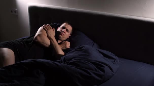 Der junge Mann erstarrte im Schlaf und rieb seine Schultern mit den Händen, um sich warm zu halten. Mit einer warmen Decke bedeckt. — Stockvideo
