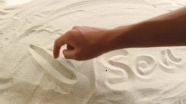 hand draws the inscription Aki Nada on the sand. Sunny coast of the sea and ocean. Symbol of rest and vacations at the resort