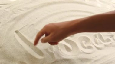 hand draws the inscription Alboran Sea on the sand. Sunny coast of the sea and ocean. Symbol of rest and vacations at the resort