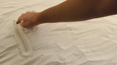 hand draws the inscription Romantic on the sand. Sunny coast of the sea and ocean. Symbol of rest and vacations at the resort
