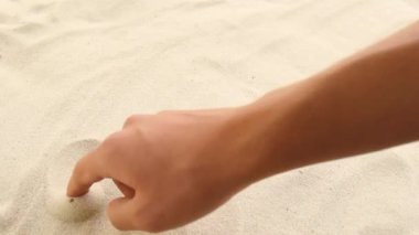 hand draws the inscription Sun on the sand. Sunny coast of the sea and ocean. Symbol of rest and vacations at the resort