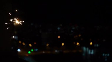 Bengal yangın çubuğu siyah arka planda ağır çekimde yanar. Havai fişekler ve bokeh