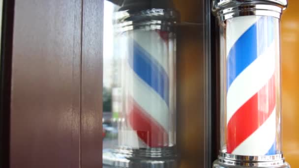 The barbers sign, Barbers pole, hangs on the wall at the entrance to the barbers shop. The three-color ribbon is spun in a plastic glass tube. Red blue white closeup — Video